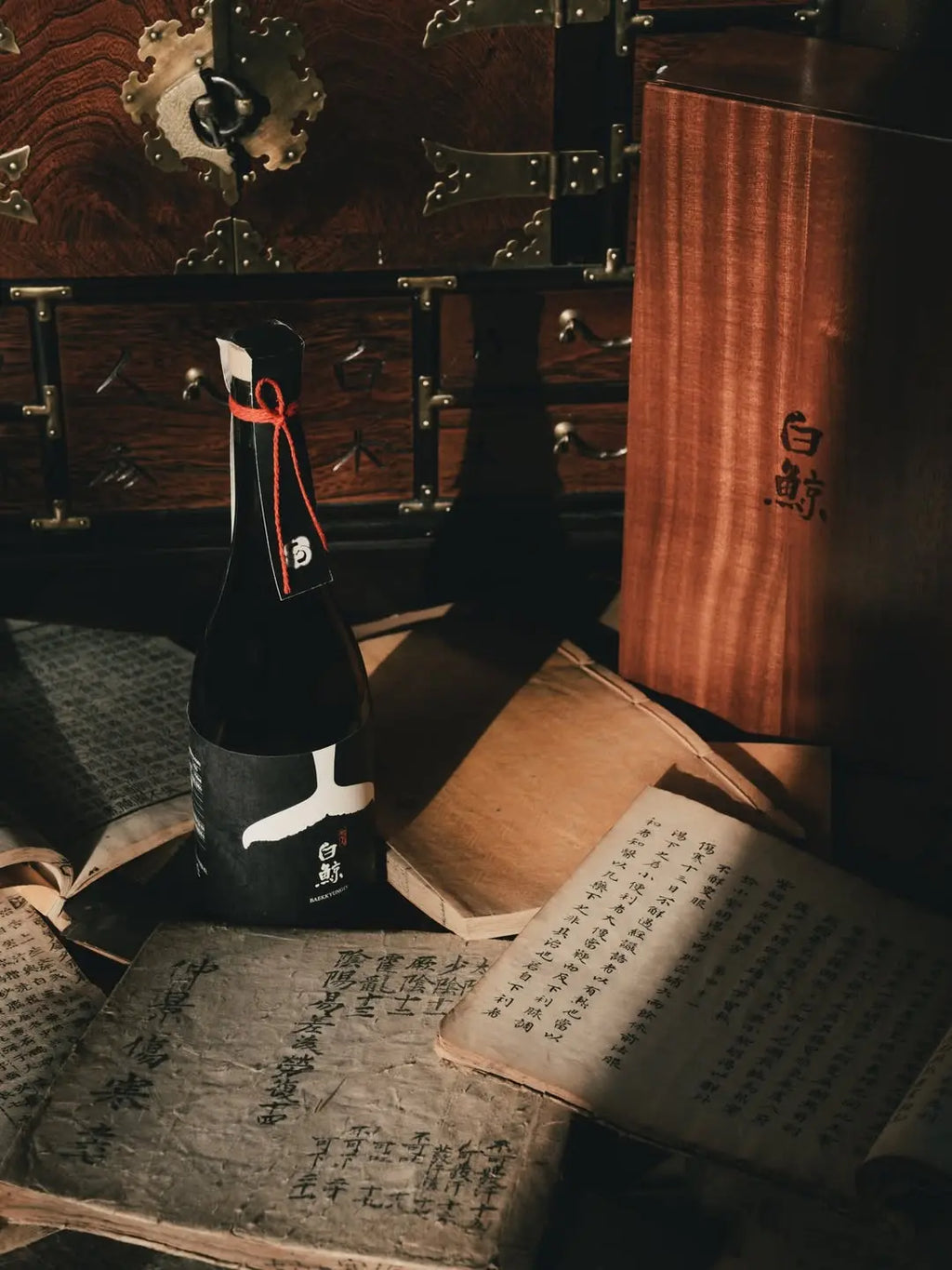 Traditional Korean rice wine bottle with a wooden chest and books written in hanja (Korean using Chinese characters) in the background. Baekkyung 15 Premium - yakju - cult