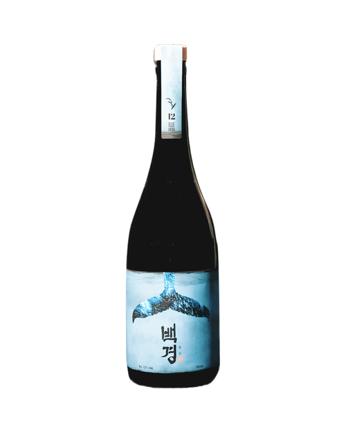 A dark glass bottle of Korean rice wine (Sake) with a light blue label featuring a whale tail graphic and Korean text, set against a plain white background. Baekkyung Blue - yakju - cult