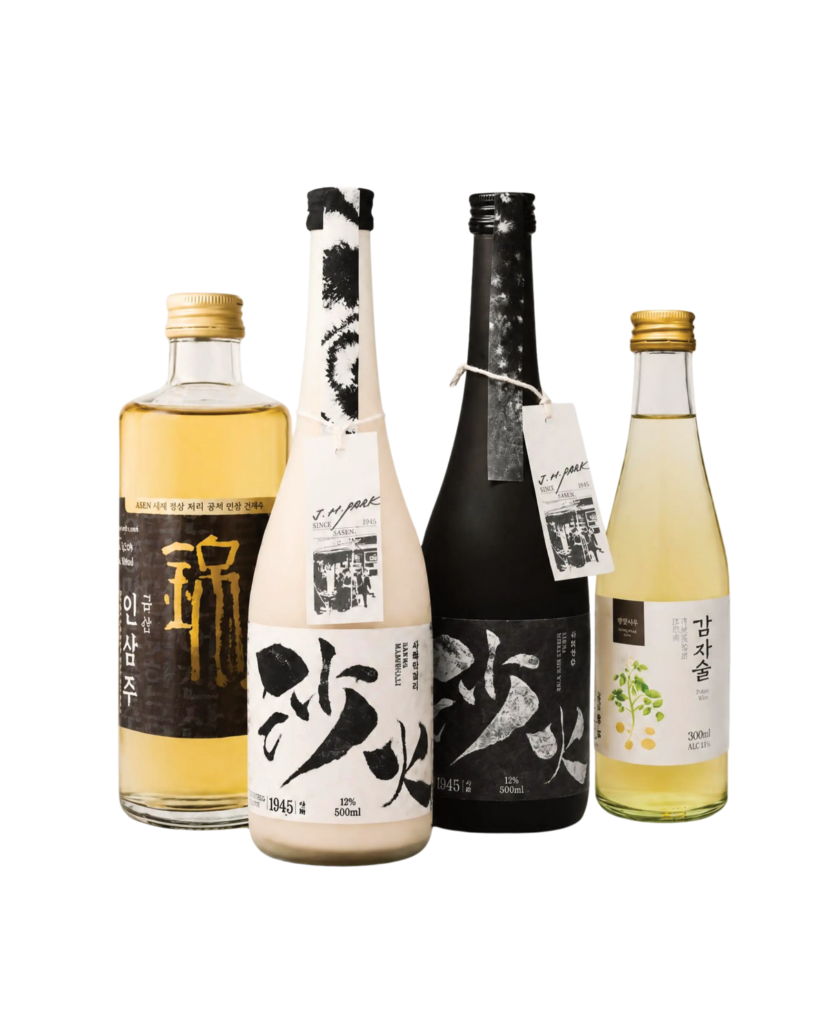 Four Korean liquor bottles arranged together on a plain white background: a clear bottle with pale golden liquid and a black label, a white bottle with a black label and hanging tag, a dark black bottle with a black label, and a pale yellow-green bottle with a green floral label.