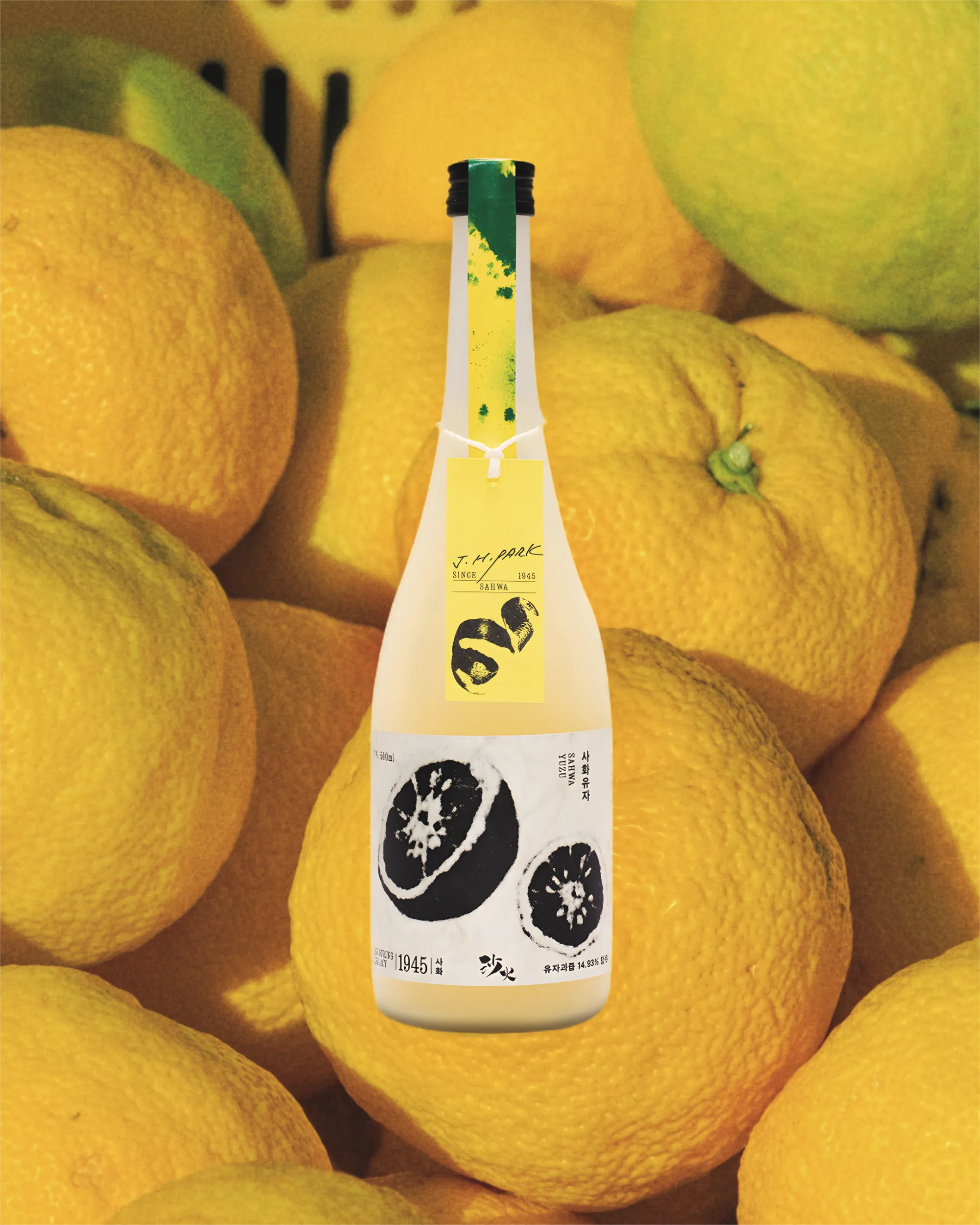A 500 ml bottle of Korean fruit wine  (Sahwa Yuzu) with a lemon design and hanging yellow product tag surrounded by yellow citrus fruit in a yellow basket.

Sahwa Yuzu - Good Tomorrow Brewery - cultsool